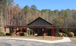 Temple Beth Israel, Meridian, Mississippi. A-frame style building with red colored portico framed by tall trees.